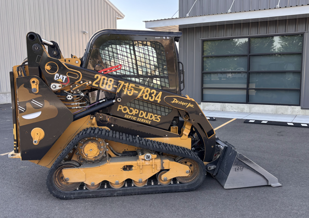 Custom gloss black wrap on CAT 259D3 for Poop Dudes Septic Service by Deviant Ink, featuring Cat yellow accents, logo, and phone number